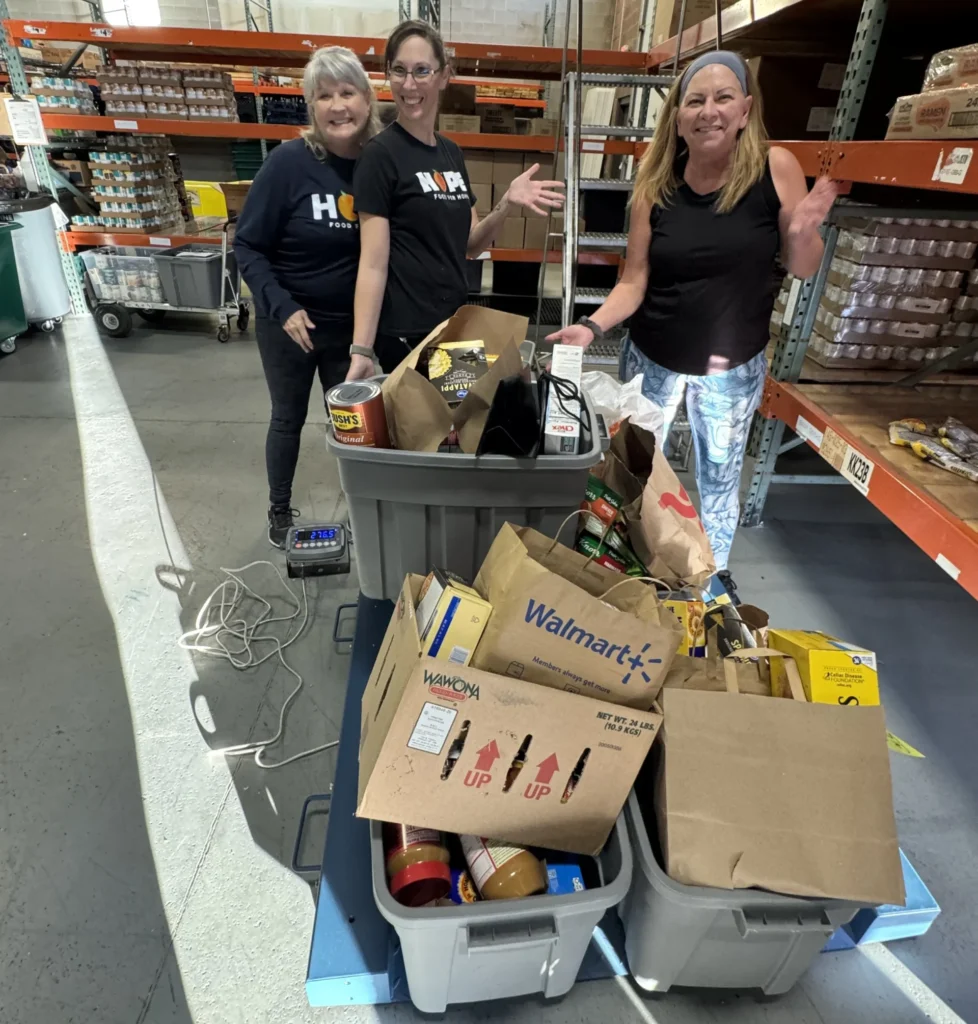 Volunteers sharing resources, food/necessity care packages, or community advocates helping a family (warm, non-profit vibe)
